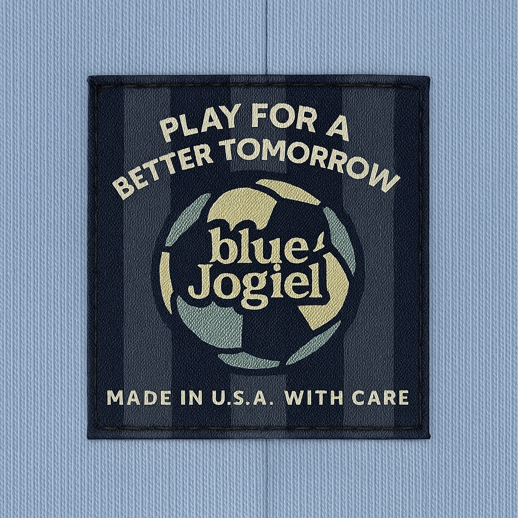 Woven label with 'Play for a Better Tomorrow' text and 'Blue Jogiel' logo and soccer ball sewn onto a blue garment on the seam.