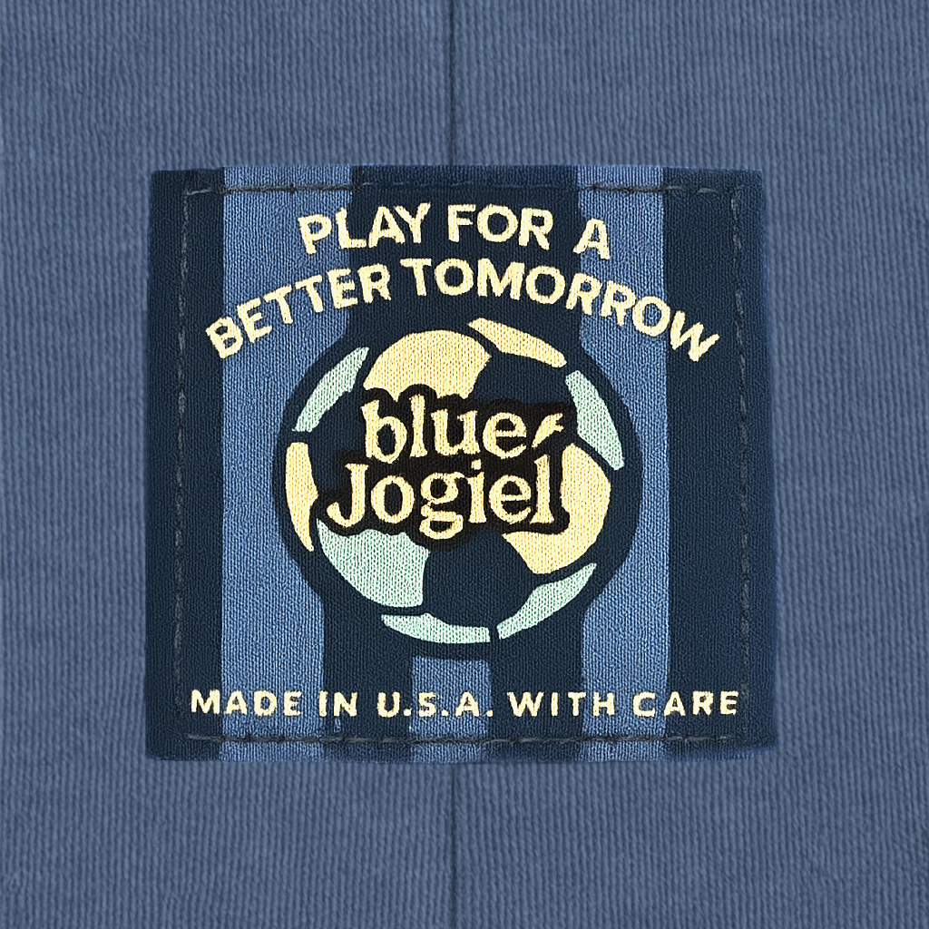 Woven label with 'Play for a Better Tomorrow' text and 'Blue Jogiel' logo and soccer ball sewn onto a white garment on the seam.