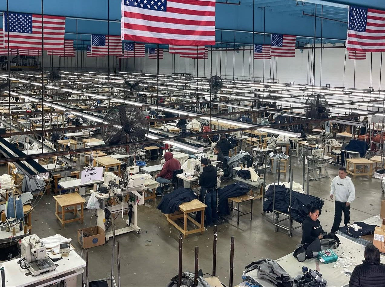 Sewing factory interior with workers and American flags handing from the ceiling.